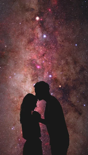 Silhouettes of a young couple under the starry sky.