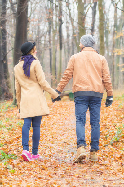 sweet couple holding hands and walking in autumn park