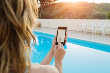 Yaz aylarında yüzme havuzu cep telefonu kullanan kız.