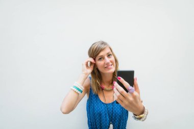 Sevimli kız önünde beyaz bir cep telefonu kullanarak duvar - cephe.