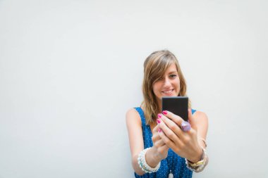 Sevimli kız önünde beyaz bir cep telefonu kullanarak duvar - cephe.