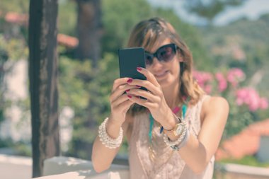 Sevimli genç kadın kullanarak / mesaj ile cep telefonu açık havada.