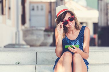 Genç kadın kentsel bir ortamda merdivenlerde otururken cep telefonu kullanarak.