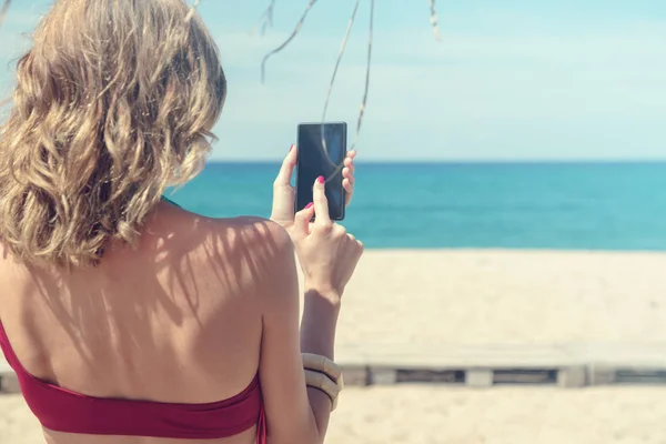 若い女性がビーチで携帯電話を使用して — ストック写真