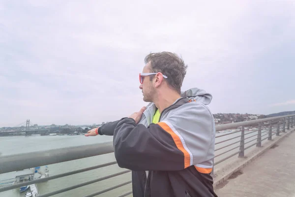 Urban jogger stretching on a big bridge.