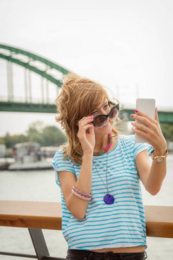 Nehri yakınında iskelede cep telefonu kullanan kız.