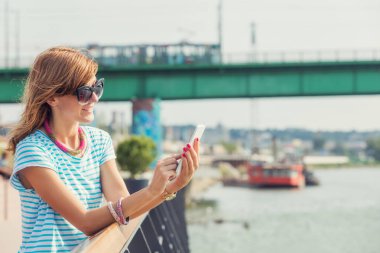 Nehri yakınında iskelede cep telefonu kullanan kız.