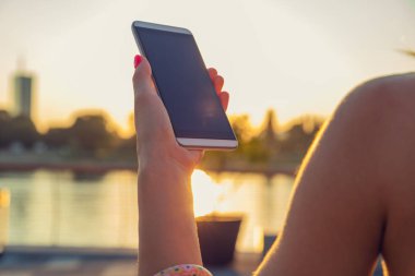 Nehri yakınında iskelede cep telefonu kullanan kız.