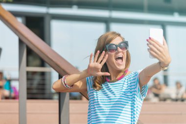 Şehir bir ortamda cep telefonu kullanarak sevimli genç kadın.