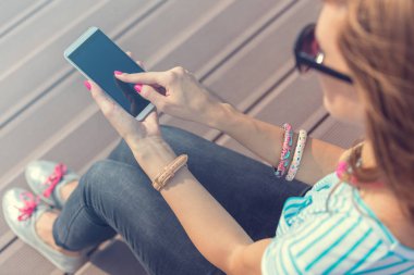 Merdivenlerin üzerinde otururken cep telefonu kullanan genç kadın.