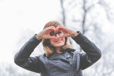 Tatlı gülen kız kalp - açık havada şekil yapma.