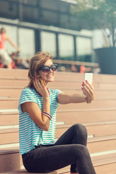 Şehir bir ortamda cep telefonu kullanarak sevimli genç kadın.