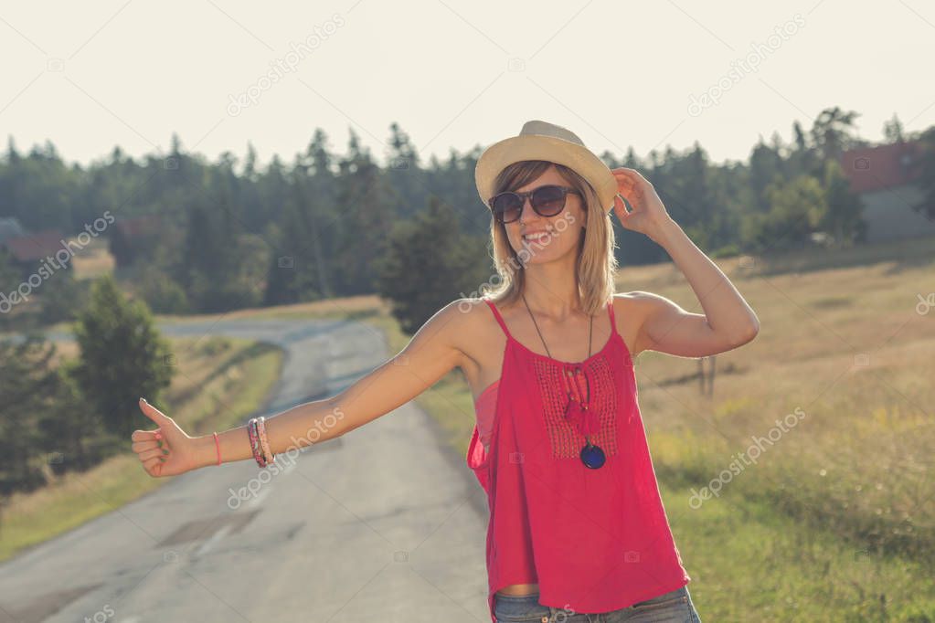 Cute young girl hitchhiking on the countryside road.