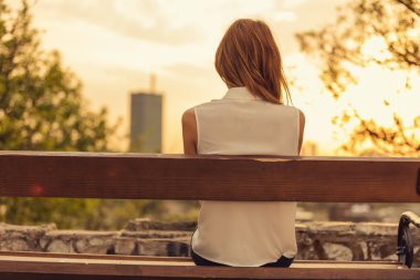 Bir bankta oturan ve uzak şehir manzara izlemek kadın.