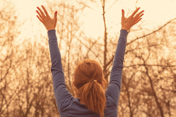 Girl with hands in the air enjoying outdoors.