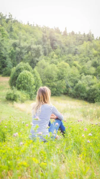 女孩坐在绿色的草地上看乡村风景 — 图库照片