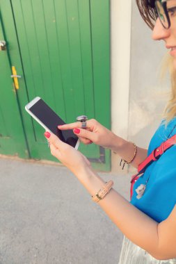 Kentsel ortamda cep telefonu tutan sevimli kadın. Optik odaklanma eldir.