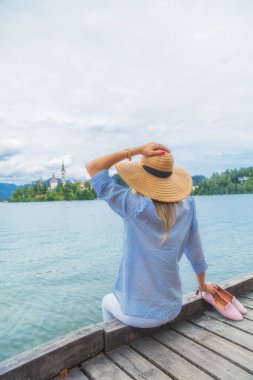 Ahşap bir iskele üzerinde oturan ve yaz zevk genç kadın.