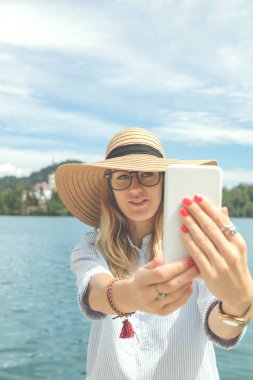 Göl kenarında cep telefonu kullanan şirin kız.