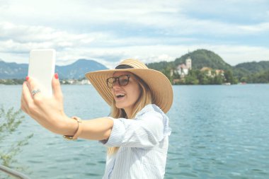 Göl kenarında cep telefonu kullanan şirin kız.