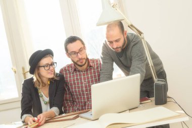 Tarafından doğal güneş ışığı yaktı bir odada genç grup insan iş planları, lap-tops ile tartışırken planları.