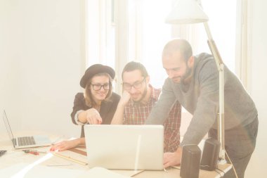 Tarafından doğal güneş ışığı yaktı bir odada genç grup insan iş planları, lap-tops ile tartışırken planları.