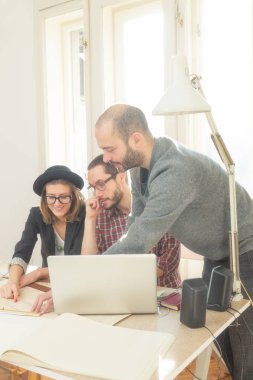 Tarafından doğal güneş ışığı yaktı bir odada genç grup insan iş planları, lap-tops ile tartışırken planları.