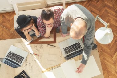 Tarafından doğal güneş ışığı yaktı bir odada genç grup insan iş planları, lap-tops ile tartışırken planları.