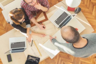 Tarafından doğal güneş ışığı yaktı bir odada genç grup insan iş planları, lap-tops ile tartışırken planları.