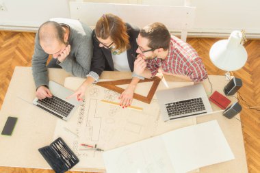 Tarafından doğal güneş ışığı yaktı bir odada genç grup insan iş planları, lap-tops ile tartışırken planları.