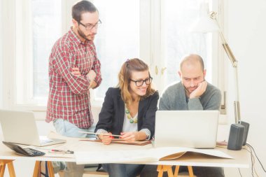 Tarafından doğal güneş ışığı yaktı bir odada genç grup insan iş planları, lap-tops ile tartışırken planları.