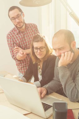 Tarafından doğal güneş ışığı yaktı bir odada genç grup insan iş planları, lap-tops ile tartışırken planları.