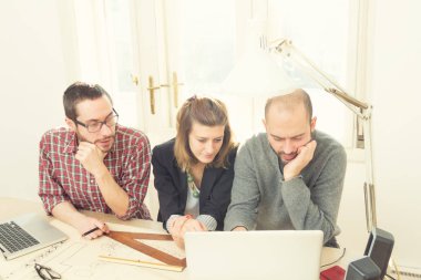 Gençlerin grup iş planları, lap-tops ile tartışırken sıradan bir oda tarafından doğal güneş ışığı yaktı planları.