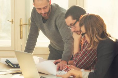 Gençlerin grup iş planları, lap-tops ile tartışırken sıradan bir oda tarafından doğal güneş ışığı yaktı planları.