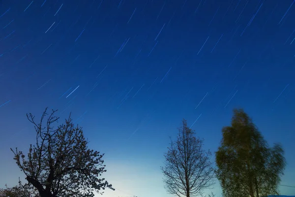 Silhouettes of a countryside with star-trails of the Milky way.