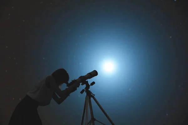 Un niño mirando a través del telescopio por la noche.