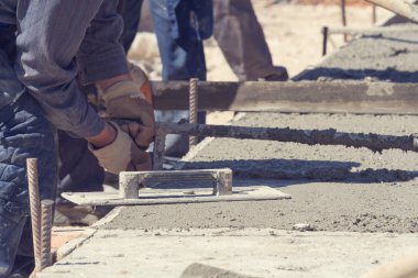 İnşaat işçisi beton kaldırımları düzlüyor..