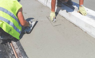 İnşaat işçisi beton kaldırımları düzlüyor..