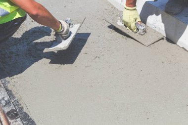İnşaat işçisi beton kaldırımları düzlüyor..