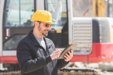 Gerçek ve sıradan inşaat işçisi tablet işini üzerinde kullanma.