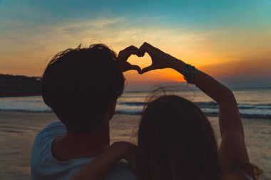 Günbatımı okyanus zamanla aşık çift yapım kalp şekli simgesi.