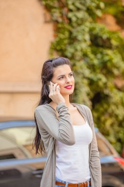 Kentsel ortamda cep telefonu kullanarak sevimli genç kadın.