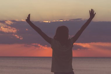 Hava ve okyanus sahne elinde bir kızla silüeti.