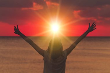 Kadın kolları geniş açık okyanus üzerinde batımını olan / deniz.