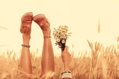 Kız çiçek tutan ve bir buğday alanında yalan.