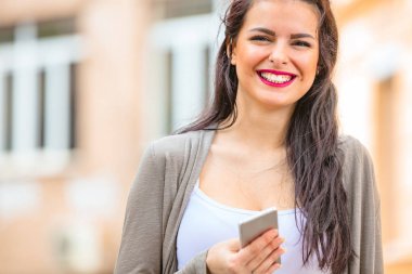 Kentsel ortamda cep telefonu kullanarak sevimli genç kadın.