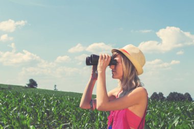 Genç kadın doğada dürbün üzerinden seyir.