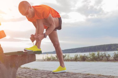 Adam Nehri yakınında bir bankta germe.