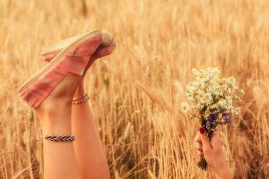 Kız çiçek tutan ve bir buğday alanında yalan.