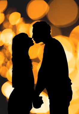 Bir çift ile silüeti de-odaklı / bokeh ışıklar.